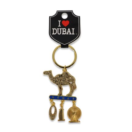 Gold-tone Dubai souvenir keychain featuring an intricately patterned filigree camel standing on a blue "Dubai" bar with dangling charms of the Burj Al Arab and Ain Dubai ferris wheel.